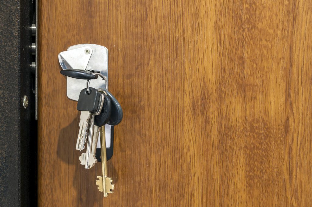 Close-up of bundle of different keys in key hole in wooden texture door.